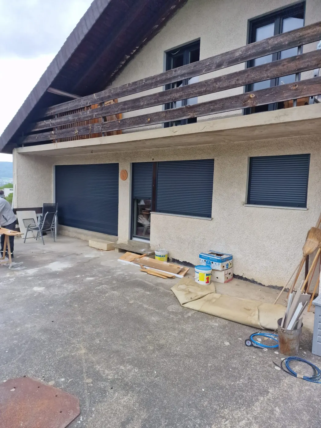 Volets roulants extérieurs anthracite installés sur plusieurs ouvertures d'une maison avec terrasse.