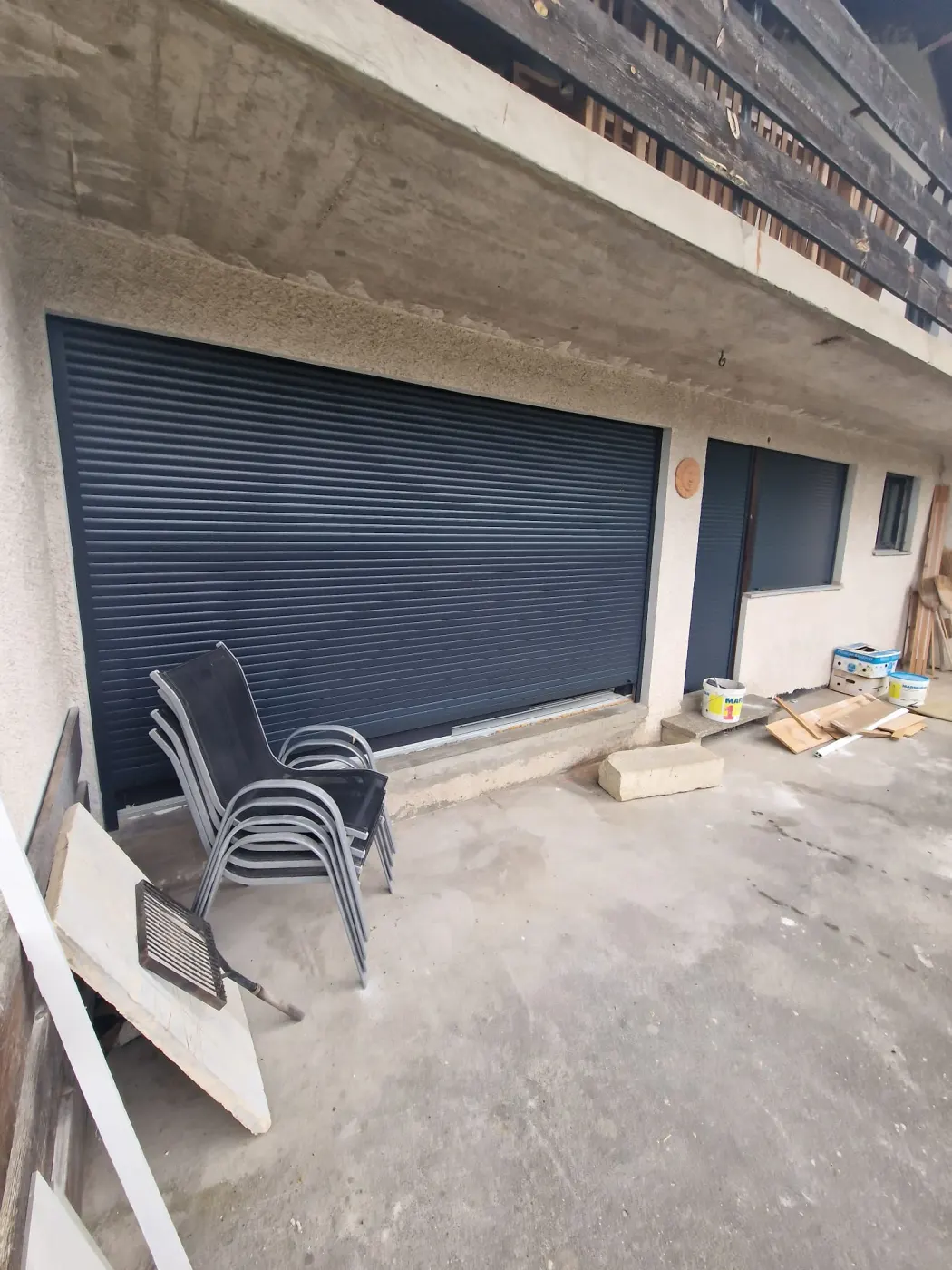 Grand volet roulant anthracite posé devant une baie vitrée donnant sur une terrasse.