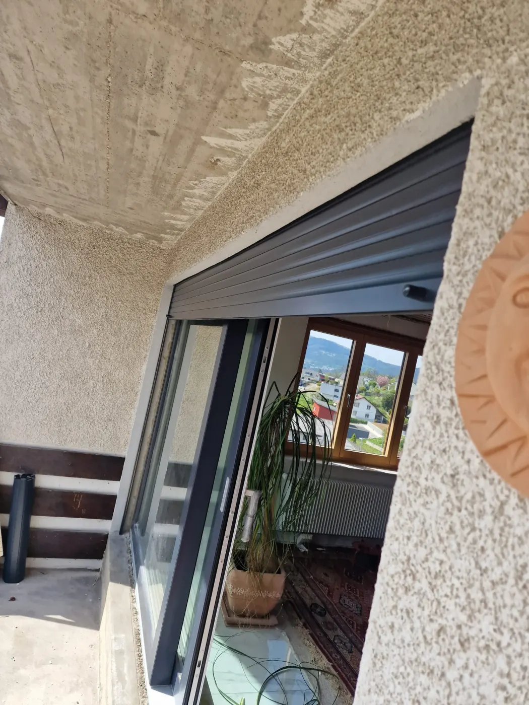 Détail d'installation d'un volet roulant extérieur sur une ouverture de balcon avec coulisses latérales.